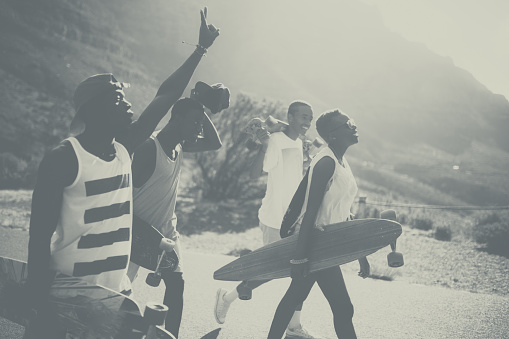 Black and white, vintage style shot of a cool group of teen skateboarders walking along a road together