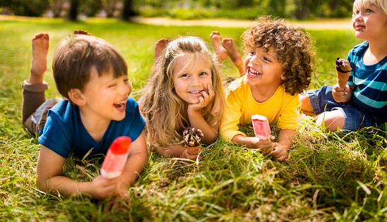 Boys and girl happily enjoying ice creams and popsicles in the park