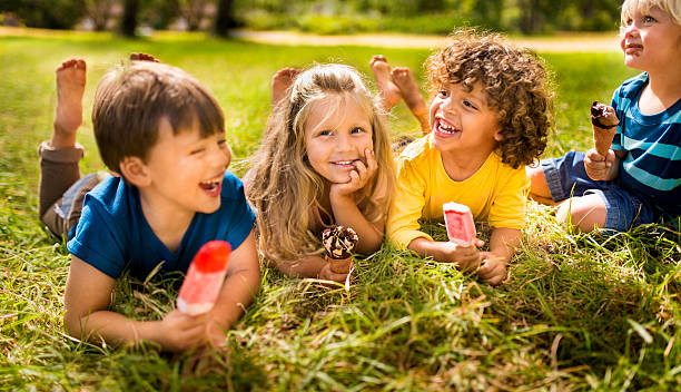 Children friends eating ice creams in park Boys and girl happily enjoying ice creams and popsicles in the park flavored ice photos stock pictures, royalty-free photos & images