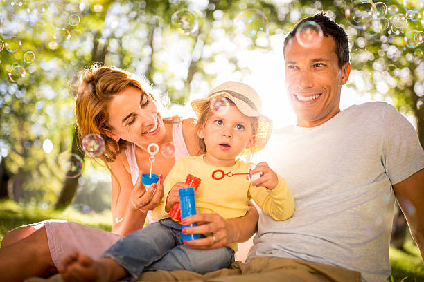 istock Girl and her parents blowing bubbles in park 474333818