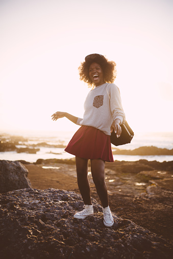 Happy Afro hipster teen girl dancing joyfully at the seaside