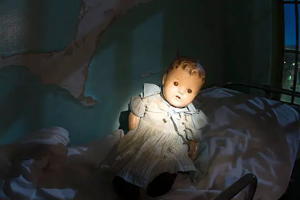 Doll sitting neglected on bed of abandoned building.