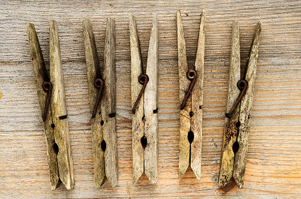 A close-up of a weathered, old-fashioned wooden clothespin with a rusted metal spring. Perfect for nostalgia, rustic, and vintage household themes. isolated on white background