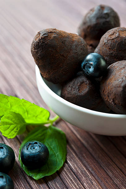 istock Chocolate truffles with blueberry and mint on wooden background 474345487