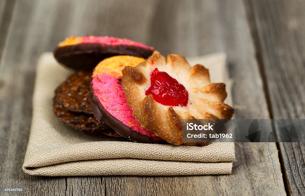 Stack of assorted cookies in cloth napkin on wood Close up image of assorted cookies resting in cloth napkin with rustic wood in background 2015 Stock Photo