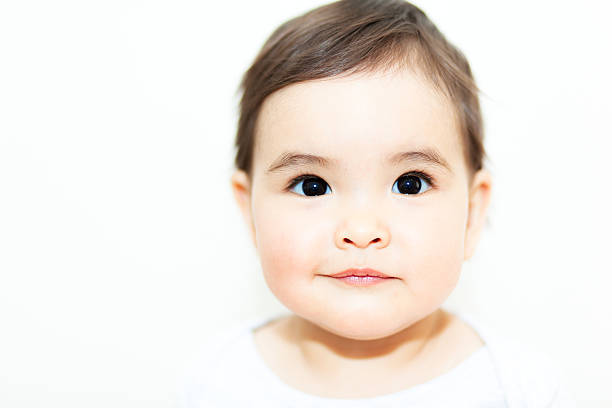 Baby girl looking at camera on the white background.