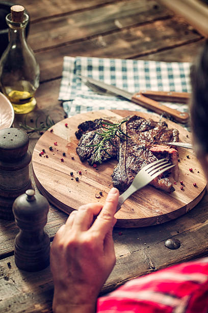 istock Young Woman Eating Medium Roasted T-Bone Steak 474350034