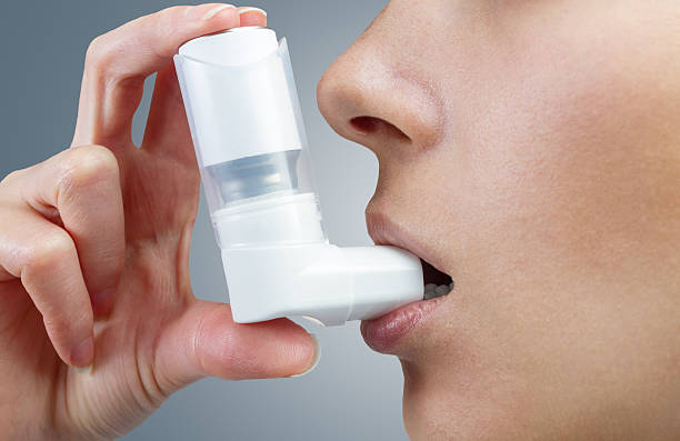 tratamiento durante un ataque de asma - inhalador de asma fotografías e imágenes de stock