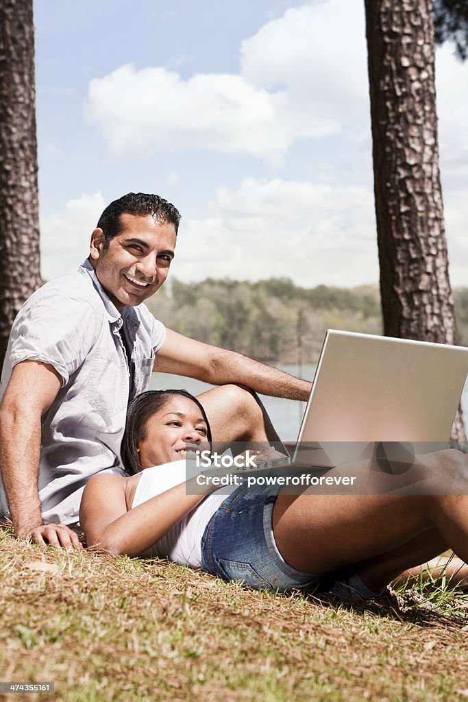 Young Couple Using Laptop in the Park Young couple using laptop computer in a park. Computer Stock Photo