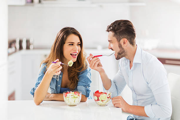 istock Young cheerful couple having fun while eating salad for lunch. 474357126