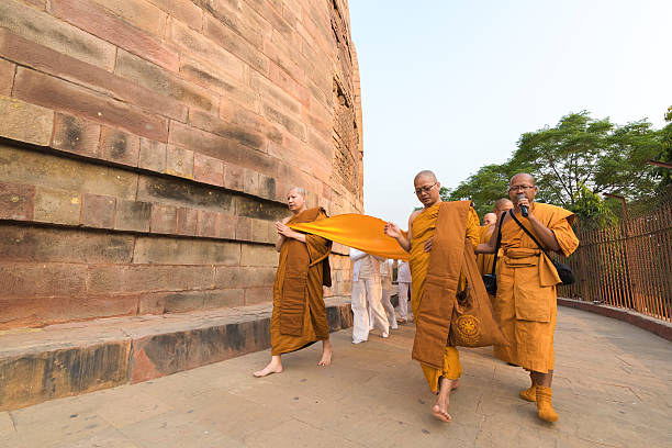 Buddhist monks, followed by pilgrims, circle the Dhamekh Stupa Sarnath, India - November 07, 2014: Buddhist monks, followed by pilgrims, circle the Dhamekh Stupa, the birthplace of Buddhism at the biggest and oldest Buddhist Stupa in Sarnath, India sarnath stock pictures, royalty-free photos & images