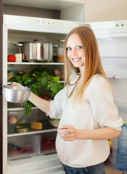 istock long-haired woman with pan near opened refrigerator 474362714