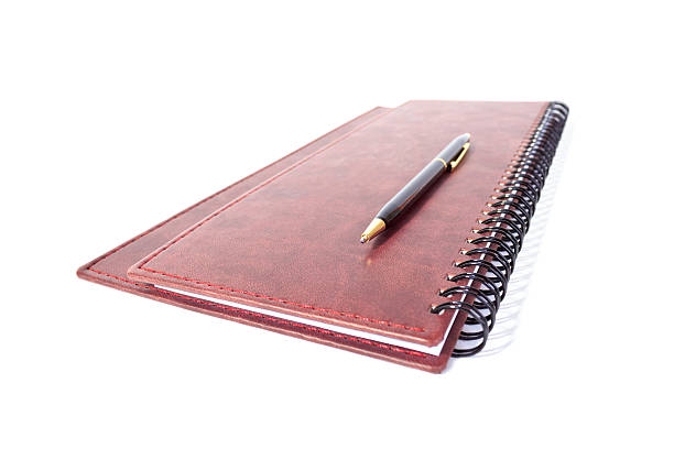 istock Black and gold expencive pen lying on spiral notebook isolated 474364318