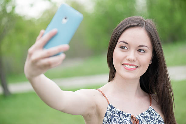 istock Smiling asian girl taking self portrait using smart phone 474364692