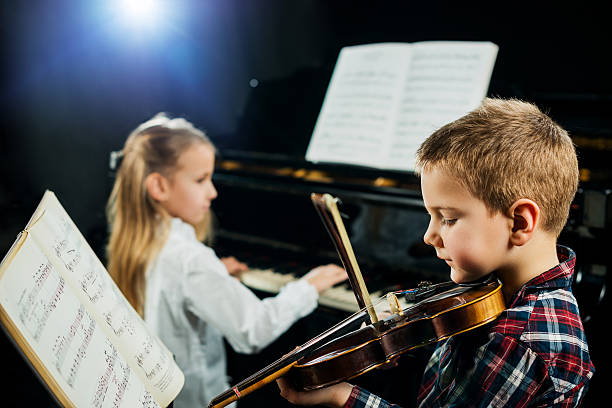 dos niños jugando con instrumentos musicales. - musical instrument violin sheet music music fotografías e imágenes de stock