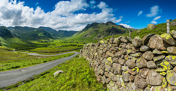 Lake Distict idyllic mountain landscape dry stone walls Cumbria UK Traditional dry stone wall undulating down the Wrynose Pass to the tranquil green summer pastures of Mickleden overlooked by the iconic mountain peaks of the Langdale Pikes deep in the idyllic landscape of the Lake District National Park, Cumbria, UK. Photo RGB profile for maximum color fidelity and gamut. langdale pikes stock pictures, royalty-free photos & images