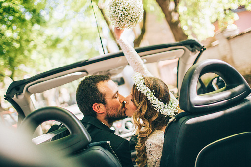 Photo of just married couple. They are kissing in the car.
