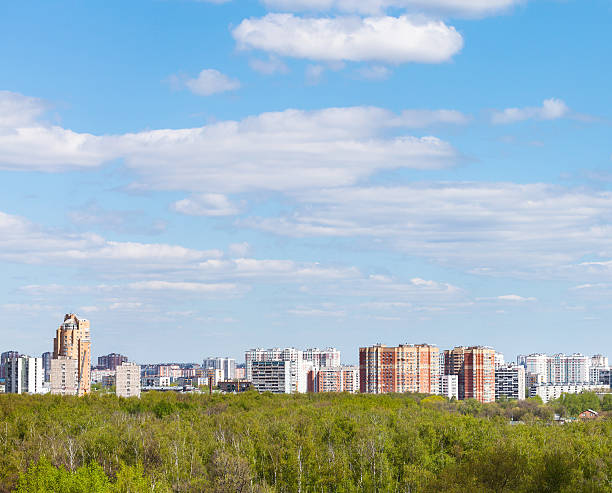 istock blue sky with clouds over city and green forest 474381748