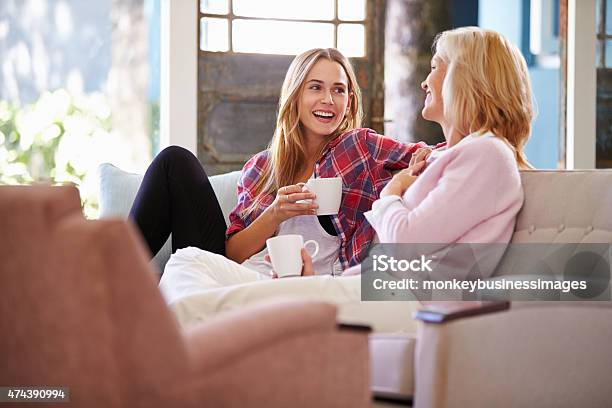 Mature Mother With Adult Daughter Relaxing On Sofa At Home Stock Photo - Download Image Now