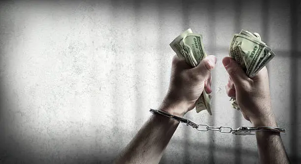 Photo of arrest for corruption - handcuffed holding dollars