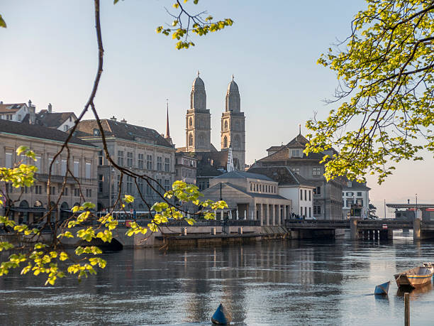 View across the River Limmat in Old Town showing Grossmunster church, old buildings, reflections on a crisp clear day in Zurich, Switzerland.