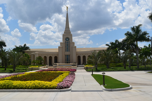 View of Church of Jesus Christ of Latter day Saints in tropical setting with Palm trees and cloudy back ground in South Florida USA.