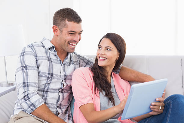 istock Couple with digital tablet sitting on sofa 474405426
