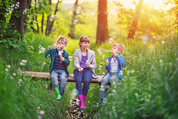 istock Kids sitting on little bridge and blowing bubbles 474405602