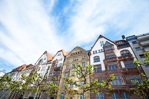Rowhouses at Rhine promenade in Düsseldorf, sunny spring day shot. Trees of alley on promenade are in foreground. Altstadt promenade.