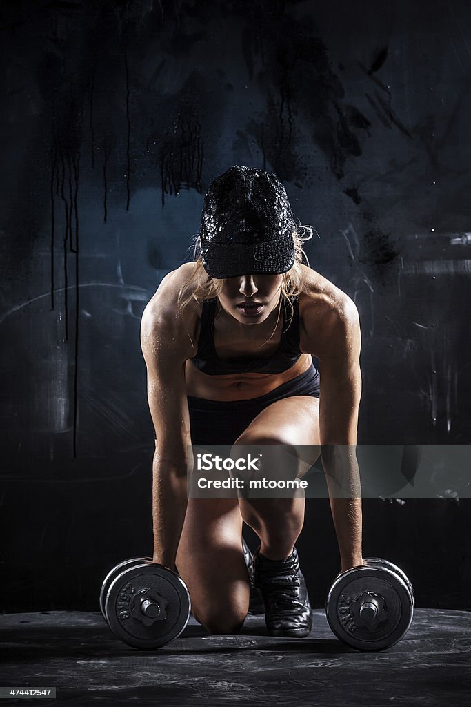 Sexy fitness Sexy woman in a cap with dumbbells on dark background Dumbbell Stock Photo