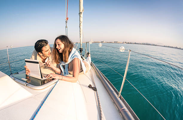 istock Young couple in love on sailboat having fun with tablet 474413356
