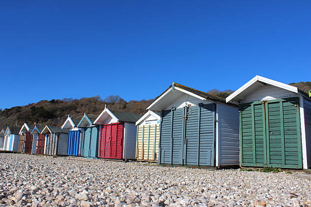istock Image of wooden beach huts on shingle / pebbles, painted bright-colours 474413578