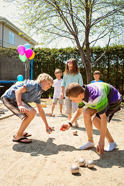 istock Little girl playing ball game outdoors with boys suburb backyard. 474420094