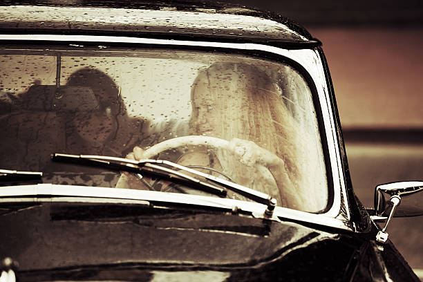 Young woman driving retro car in the rain stock photo