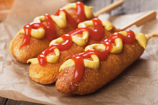 Corn dog, fried sausage in batter with mustard and ketchup