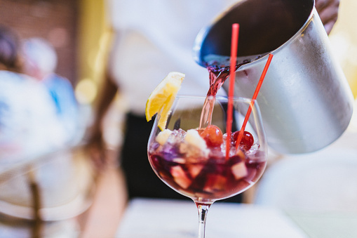 Refreshing sangria being poured in a glass by a waiter.