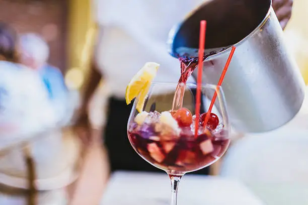 Refreshing sangria being poured in a glass by a waiter.