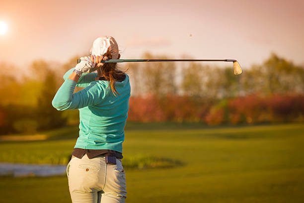 Woman golf player hitting ball.
