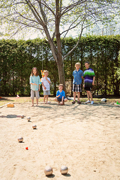 istock Little girl playing ball game outdoors with boys suburb backyard. 474423734
