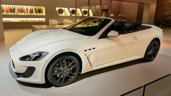 Brussels, Belgium - January 14, 2014: Maserati GranCabrio or GranTurismo Convertible open sports car on display during the 2014 Brussels motor show. Two girls are standing behind an information desk in the background.