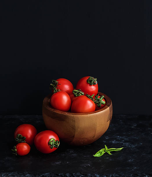 istock Ripe cherry-tomatoes in wooden bowl with basil leaves 474424704