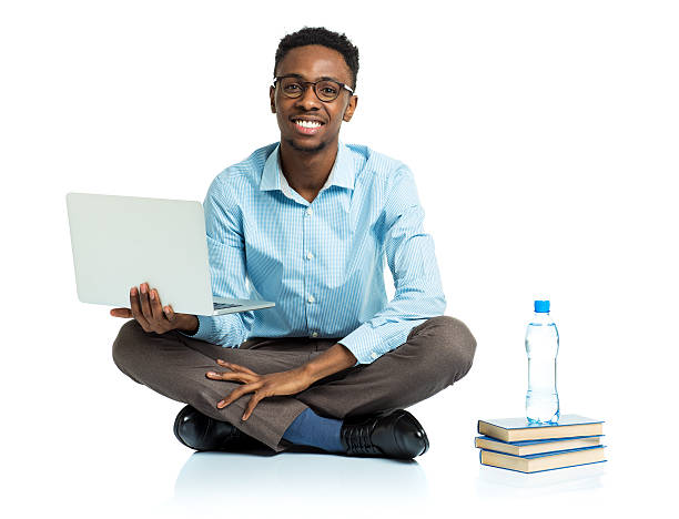 szczęśliwy african american college student siedzi z laptopa na biały - sitting young men book isolated on white zdjęcia i obrazy z banku zdjęć