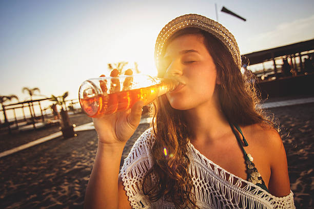 istock Girl drinking beer at the beach 474428722