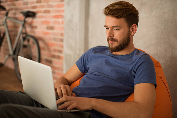 istock Man sitting in bean bag and using laptop. 474428814