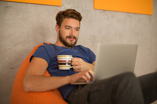 istock Man sitting in bean bag and using laptop. 474428822