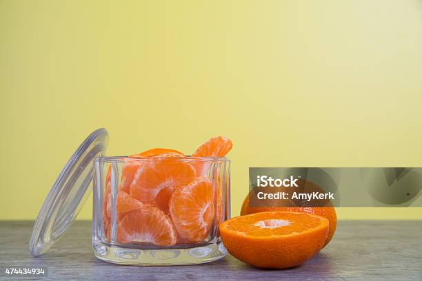 Mandarin Oranges In A Glass Jar With A Yellow Background Stock Photo - Download Image Now