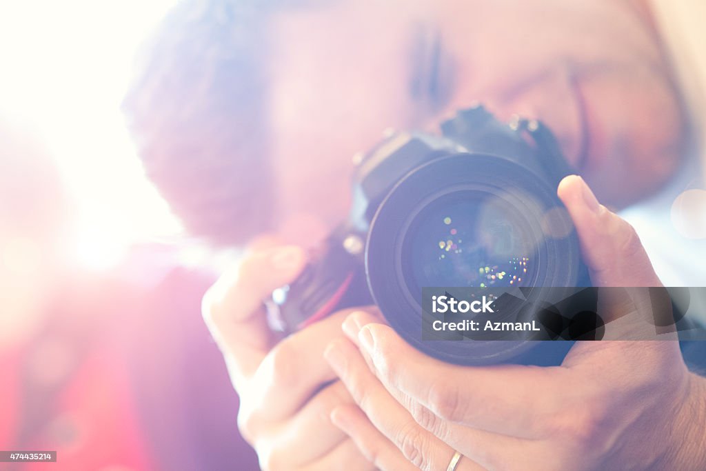 Photographer at work Young photographer holding aprofessional digital camera and taking pictures. 2015 Stock Photo