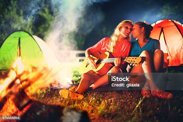 Two Girls Playing Guitar By Campfire Stock Photo - Download Image Now - Bonfire, Campfire, Adolescence