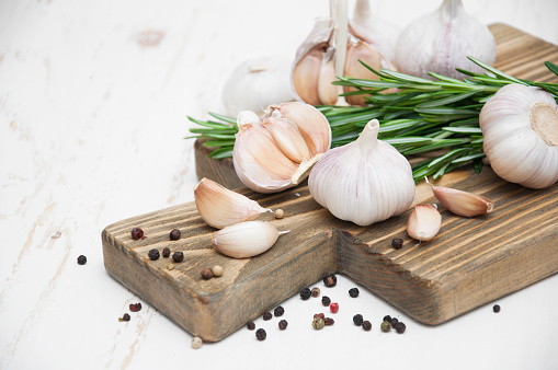Fresh garlic, rosemary, and pepper peas on wooden background