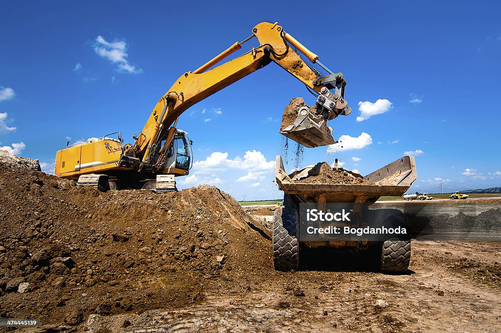 Industrial truck loader excavator moving earth and unloading int Industrial truck loader excavator moving earth and unloading into a dumper truck Construction Site Stock Photo